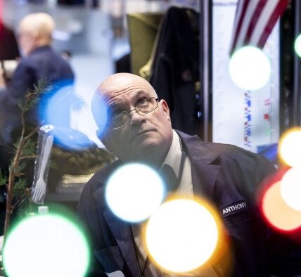 A trader works on the floor as news of the Federal Reserve rate cut decision shows on a TV at the New York Stock Exchange