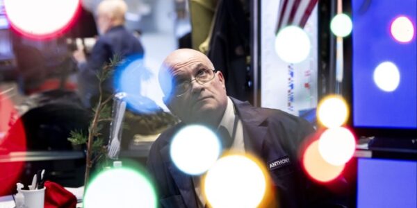 A trader works on the floor as news of the Federal Reserve rate cut decision shows on a TV at the New York Stock Exchange